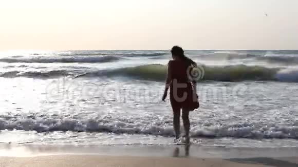 一位留着长发的年轻女子玩着海浪感受大海海景视频的预览图