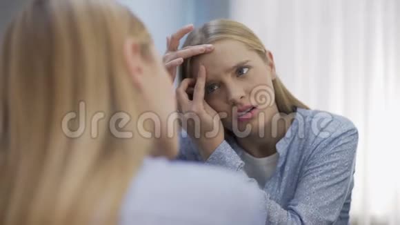担心年轻女子在镜子前脸上流着粉刺缺乏安全感视频的预览图