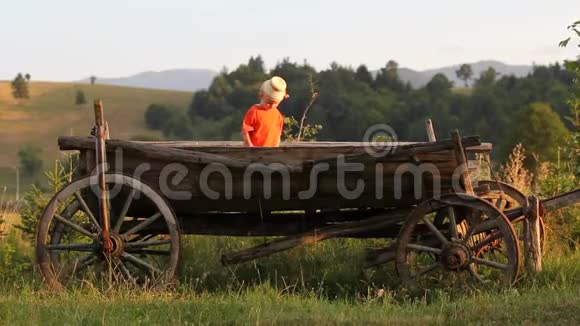 可爱的农民孩子戴着传统的帽子坐在传统的木车里视频的预览图