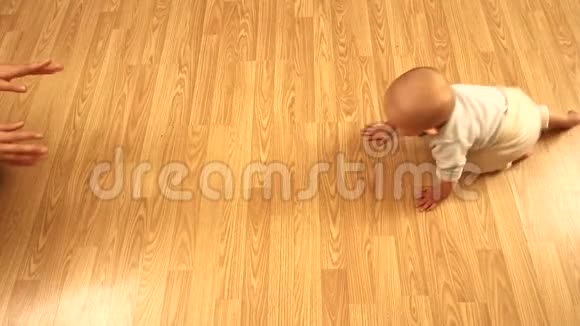 婴儿在地板上张开双臂向母亲爬行视频的预览图