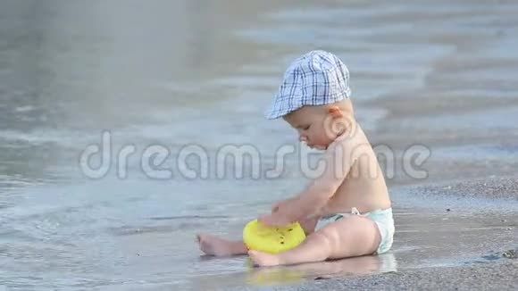 小宝宝坐在海边在波浪中松开玩具视频的预览图