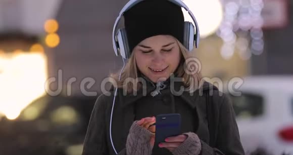 冬天女人在晚间城市的智能手机里写信息视频的预览图