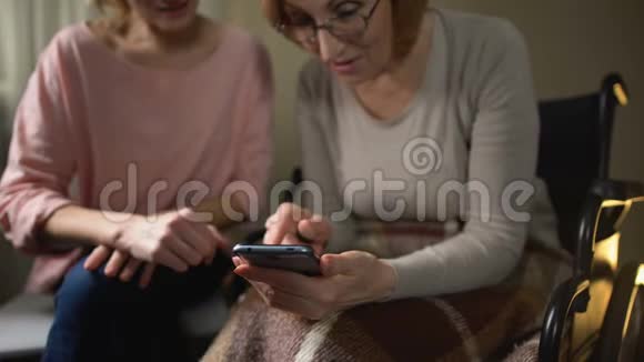 友好的老妇人学习如何使用智能手机女儿展示移动应用程序视频的预览图
