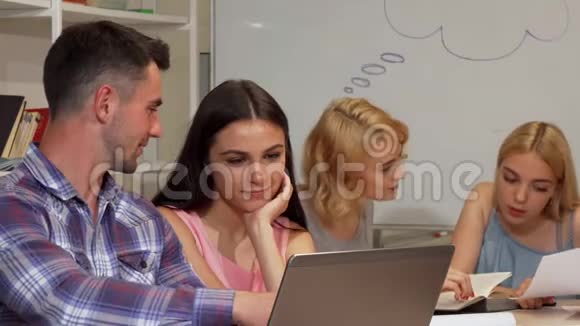 两个年轻开朗的学生在笔记本电脑上讨论他们的项目视频的预览图