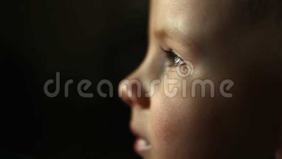 疲惫的孩子在电视前迷失错误的教育男孩的肖像悲伤的童年黑色的背景眨眼眼睛视频的预览图
