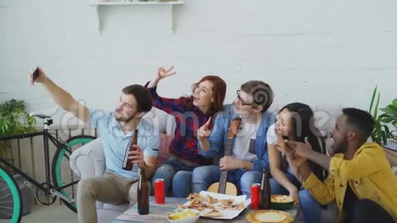 快乐的学生朋友在智能手机上自拍在分享啤酒和披萨的时候摆姿势视频的预览图