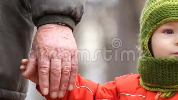 可爱的孙子握着爷爷的手简单的接近手势视频的预览图