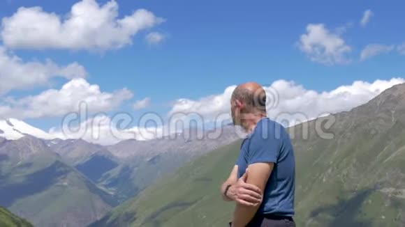 一位旅行者站在高山上看着埃尔布鲁斯的山顶视频的预览图