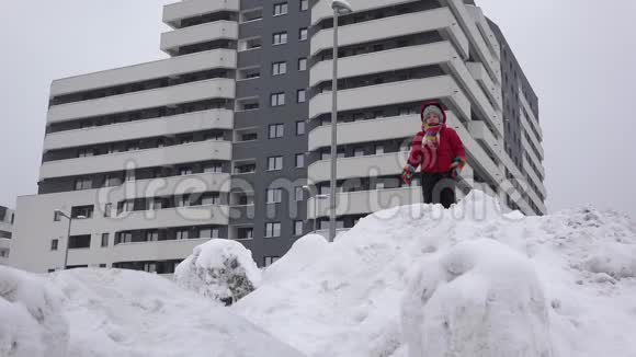 小孩子在靠近公寓街区的雪山上滑行创造性的童年视频的预览图