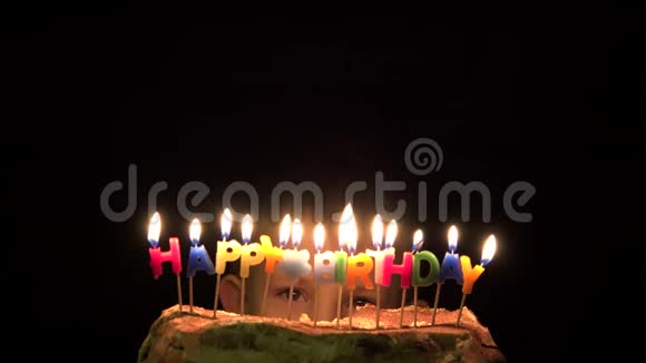 有趣的男孩眼睛在蛋糕后面焦急地看着孩子吹生日蜡烛视频的预览图