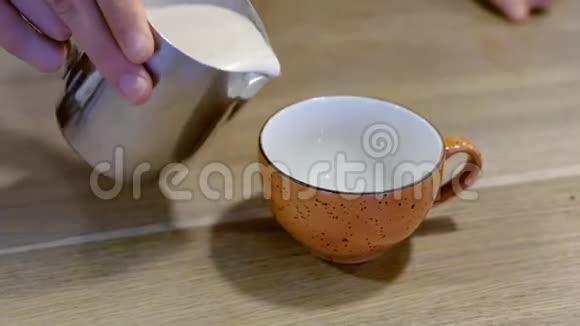 专业的咖啡师把新鲜的卡布奇诺咖啡从一个水罐倒到另一个杯子里手特写视频的预览图