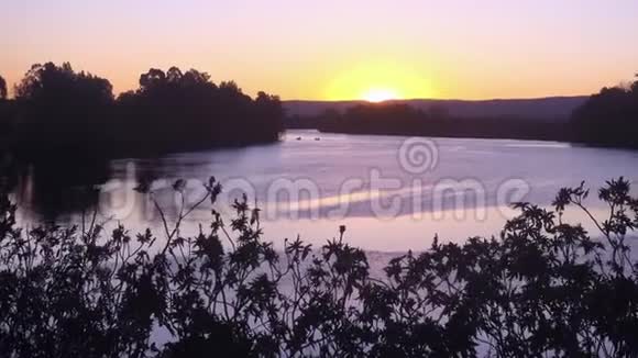 太阳落在澳大利亚悉尼以西的温莎的霍克斯伯里河上远处有两艘渔船和蓝船视频的预览图