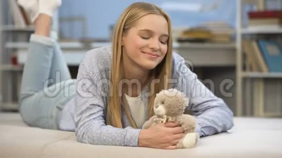 微笑的女学生抱着她的玩具熊在卧室童年的家舒适视频的预览图