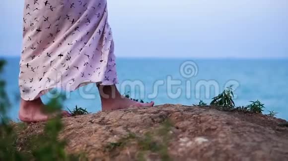 在日出的时候穿着轻装的女孩走在海上的悬崖边缘视频的预览图