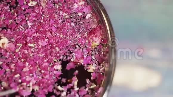 在玻璃碗中用勺子搅拌一片干燥的紫色花瓣视频的预览图