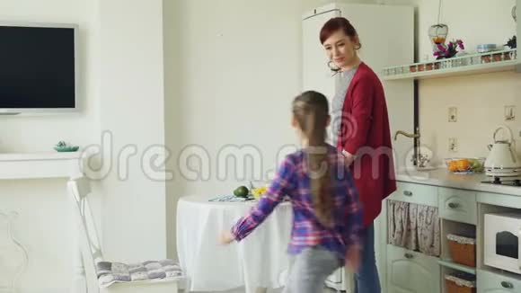 快乐的母亲和可爱的女儿在现代厨房愉快地交谈当女孩来的时候妈妈在做饭家庭食物视频的预览图