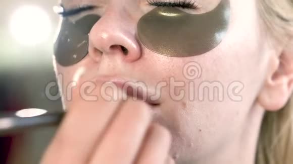有眼贴的女性面部特写化妆师应用自然的外观唇彩视频的预览图