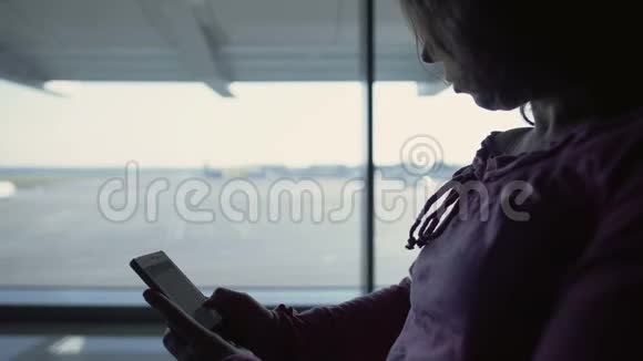 女游客在网上看书等待航班花时间在机场视频的预览图