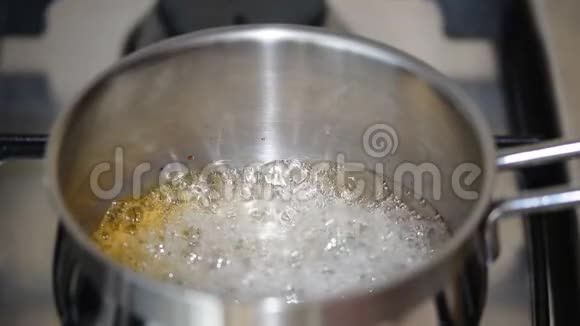 将焦糖糖浆放入锅中的炉子上煮沸煮糖混合物制作金箍棒视频的预览图