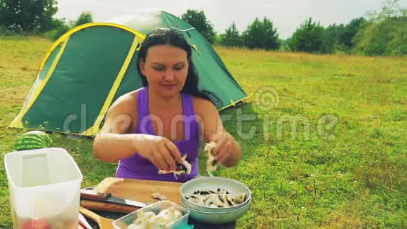 靠近帐篷的一位妇女在一张木桌上把切碎的蘑菇铺成一个盘子视频的预览图