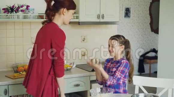 快乐的妈妈和可爱的有趣的女儿玩拍手游戏在家厨房做饭时玩得很开心家庭视频的预览图