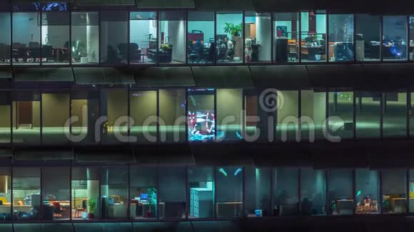 晚上在玻璃办公楼工作有许多办公室有玻璃墙和窗户时间推移视频的预览图