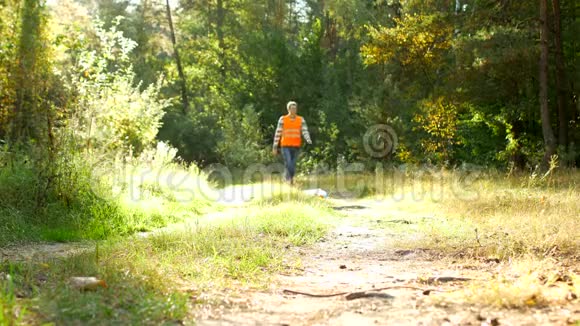 男志愿者在信号橙色背心清洁森林垃圾清洁森林和自然视频的预览图