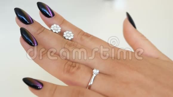 女人拿着钻石的耳环在手指间看着它的手一位女士正在珠宝店视频的预览图