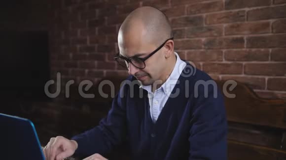 一个英俊的中年男子在办公室里坐在桌子旁在做商业项目时用笔记本电脑打字视频的预览图