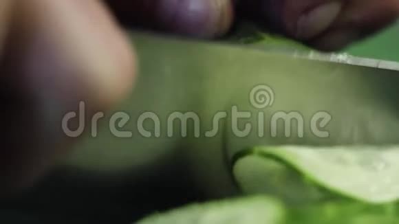 绿色餐桌上用锋利的大刀切黄瓜的特写视频的预览图