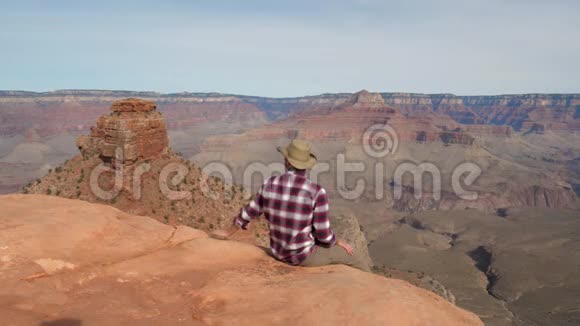 白种人坐在深渊边缘看着大峡谷的惊人景象视频的预览图