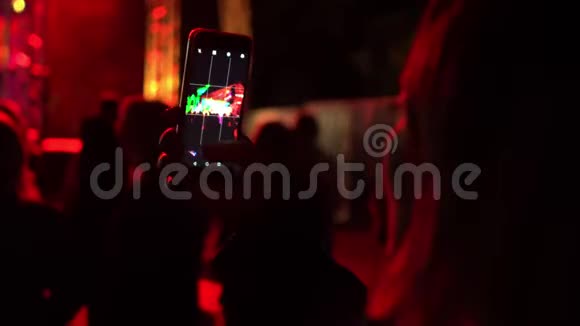 年轻女子用智能手机在人群中录制夏季音乐会视频的后视频镜头视频的预览图