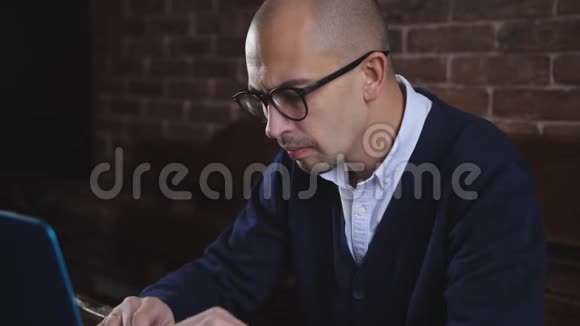 一个英俊的中年男子在办公室里坐在桌子旁在做商业项目时用笔记本电脑打字视频的预览图