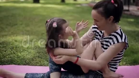 穿运动制服的妈妈和女儿在公园的草坪上玩视频的预览图