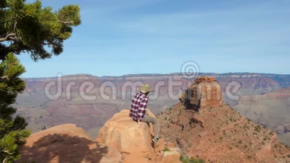 白种人坐在岩石边缘看着大峡谷的奇妙景色视频的预览图