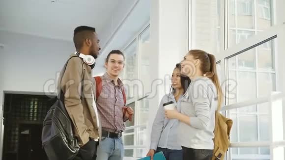 大学里四个多民族的学生站在白色宽敞的大厅里积极地交谈着他们视频的预览图
