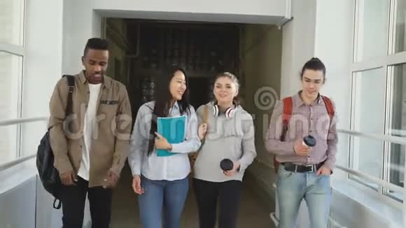 多民族学生在白色宽敞的大学走廊上散步通过考试后愉快地交谈视频的预览图