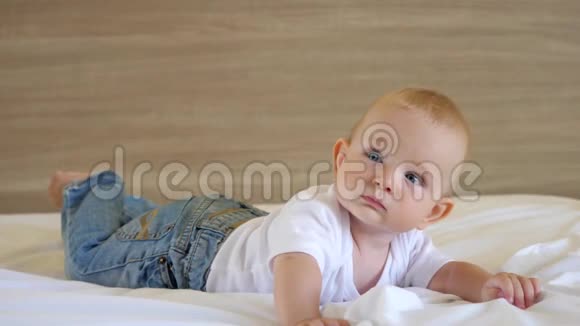 可爱的婴儿躺在他的肚子上看着蓝眼睛的相机视频的预览图