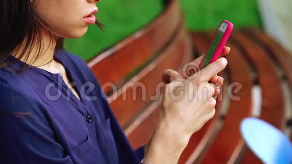 女人坐在长凳上用智能手机近景视频的预览图
