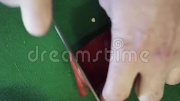 在绿桌上用刀将红辣椒切成细条状视频的预览图
