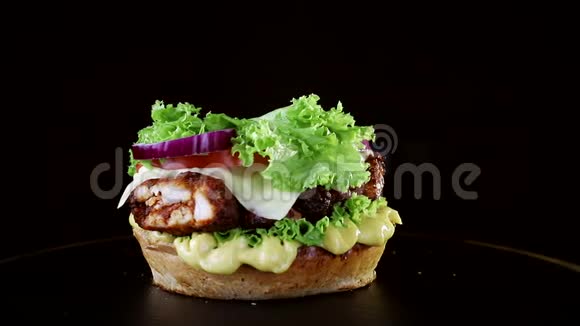 发髻缓缓落在汉堡上快餐黑色背景美味汉堡视频的预览图