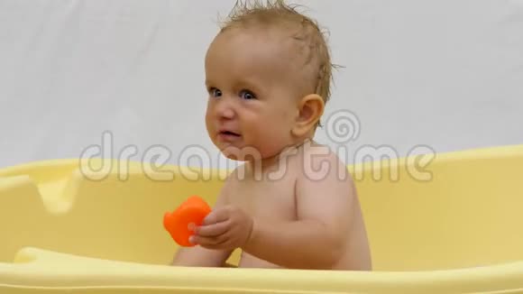 可爱的小宝宝玩彩色鸭子玩具在浴缸里洗澡时开心和微笑视频的预览图