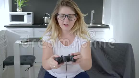 游戏成瘾兴奋的女性在家坐在扶手椅上玩电子游戏视频的预览图