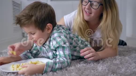游戏与食物可爱的孩子与母亲吃甜玉米棒从盘子躺在室内视频的预览图