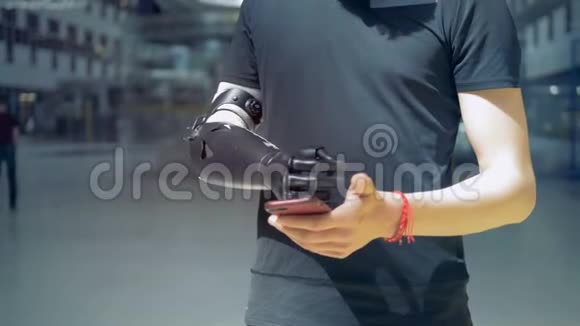 一个带仿生假肢的男人看着他的手机视频的预览图