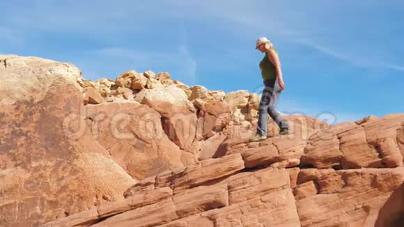 运动成熟的胖女人小心地沿着峡谷的红岩走下去视频的预览图