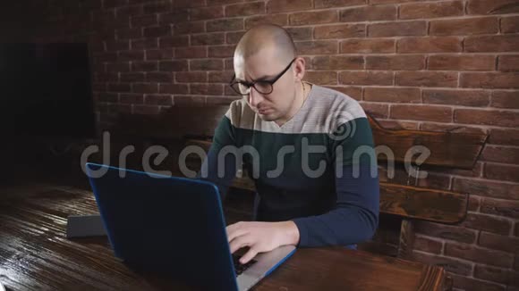 戴眼镜的人热衷于在笔记本电脑上工作一位男作家正在笔记本电脑键盘上打字视频的预览图