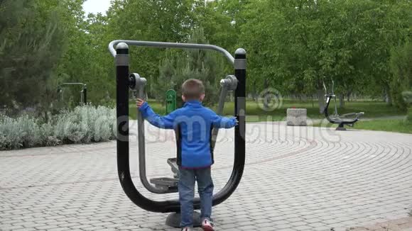 公园健身机里的小孩背着一个孤立的男孩视频的预览图