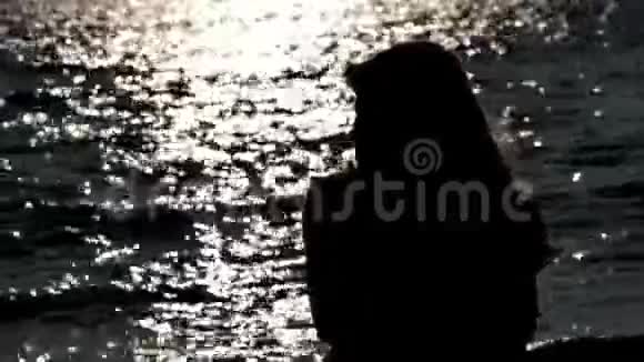 日出时欣赏波光粼粼大海的女人玩弄头发的女人视频的预览图