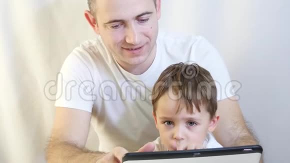 爸爸和他的儿子在白色背景上玩平板电脑幸福家庭的概念视频的预览图